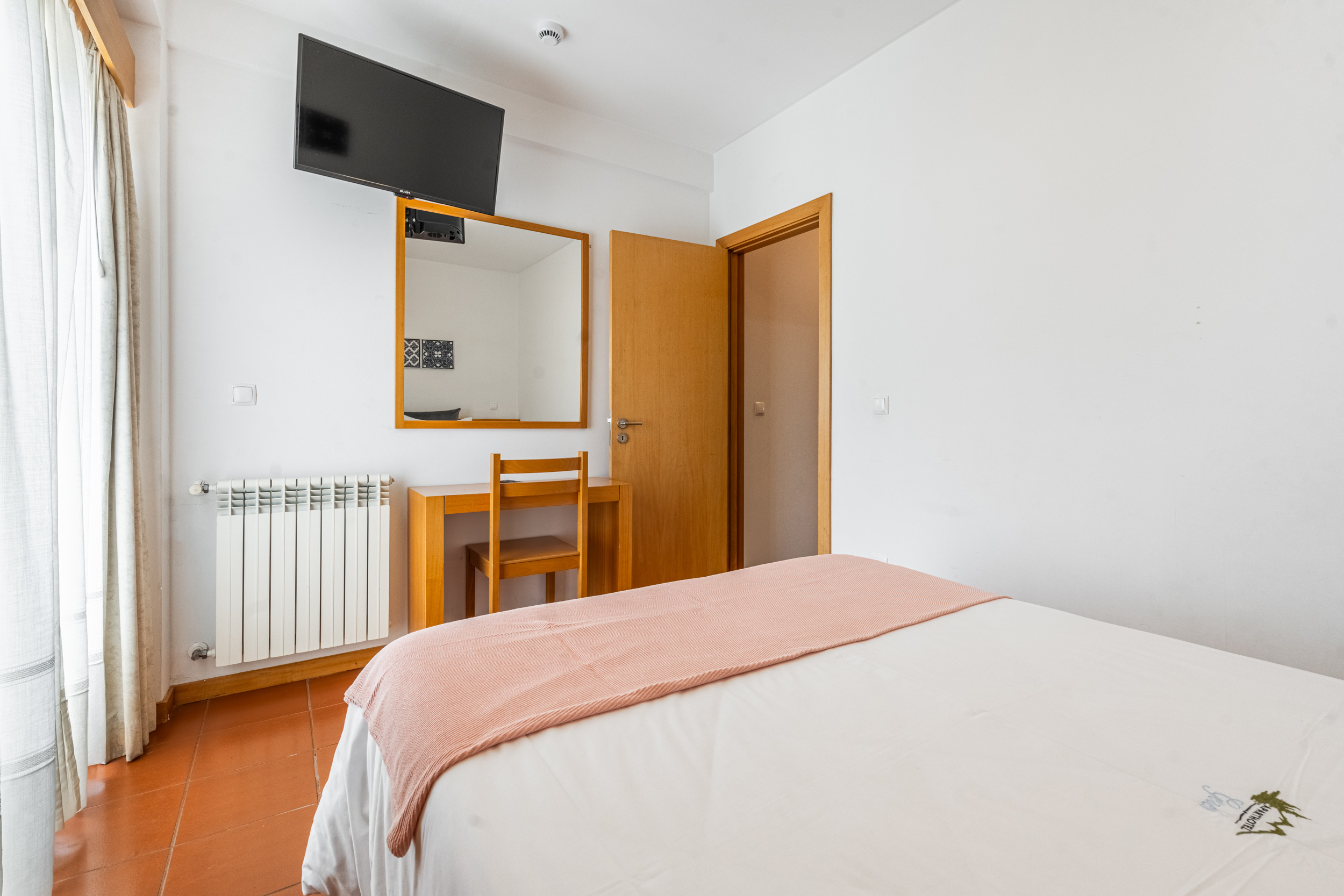 Quarto com secretária, TV e radiador